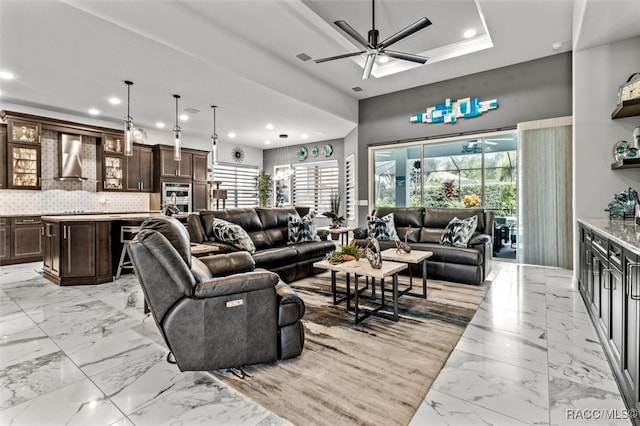 living room with a raised ceiling and ceiling fan