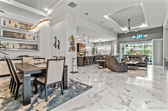 dining area with a raised ceiling, ceiling fan, and ornamental molding