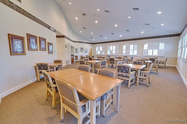 dining area featuring ornamental molding, light carpet, and high vaulted ceiling