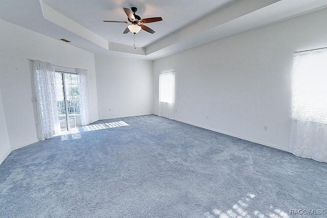 carpeted empty room with ceiling fan and a tray ceiling