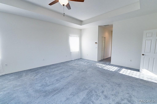 carpeted spare room with ceiling fan and a raised ceiling