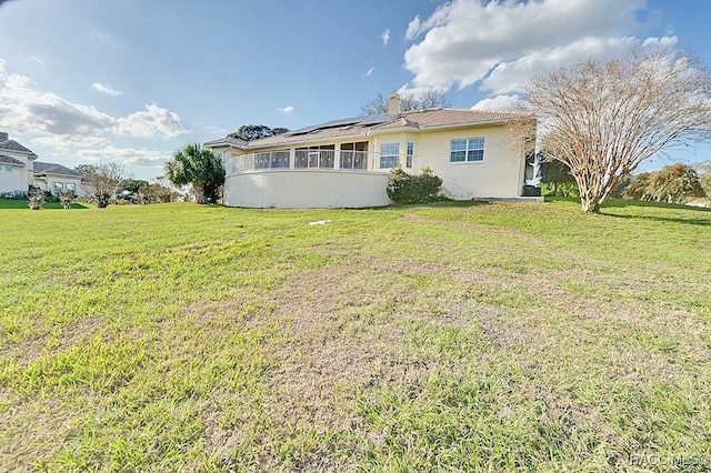 back of property with a yard and solar panels