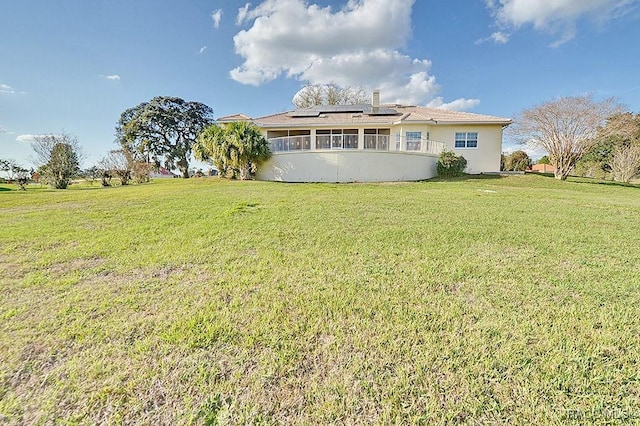 back of property with a yard and solar panels