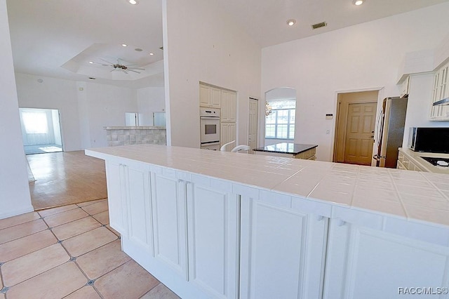 kitchen with a wealth of natural light, white cabinetry, and stainless steel fridge