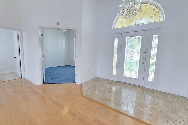 foyer entrance with light hardwood / wood-style floors, a notable chandelier, and a towering ceiling