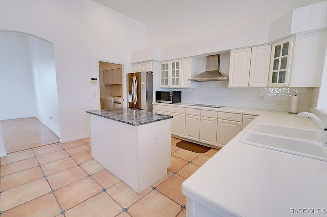 kitchen featuring appliances with stainless steel finishes, wall chimney range hood, a kitchen island, sink, and white cabinetry