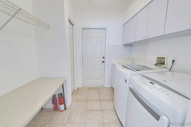 washroom featuring cabinets, washer and dryer, and light tile patterned floors