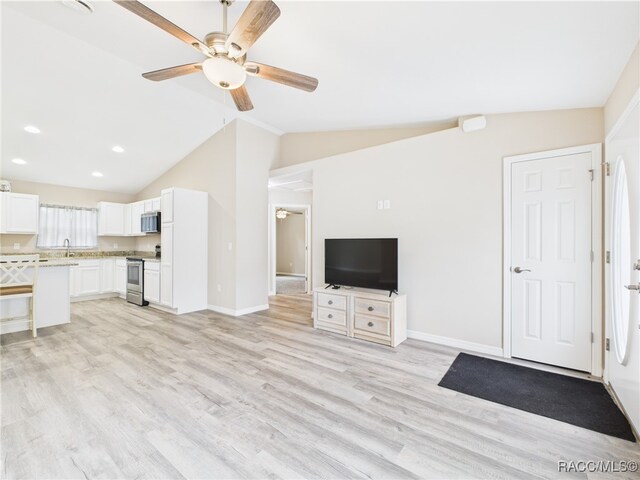 178 W Navarro Pl, Citrus Springs, FL 34434 - unfurnished living room featuring ceiling fan, vaulted ceiling, light wood-style floors, baseboards, and a sink
