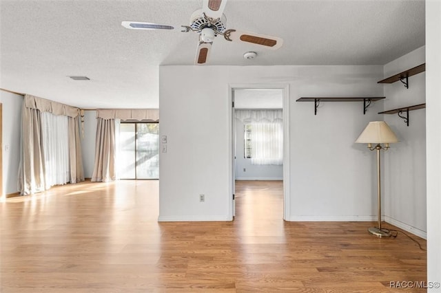 unfurnished room with a textured ceiling, light hardwood / wood-style floors, a wealth of natural light, and ceiling fan