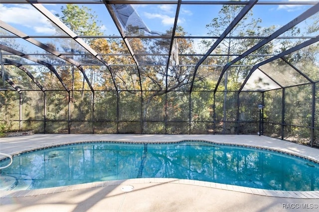 view of pool featuring glass enclosure and a patio area