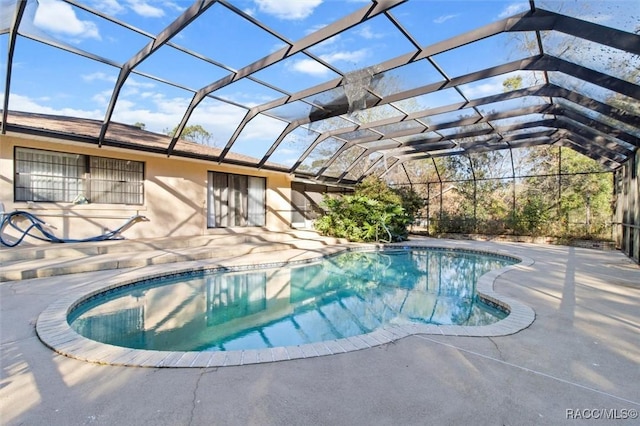 view of pool featuring glass enclosure and a patio