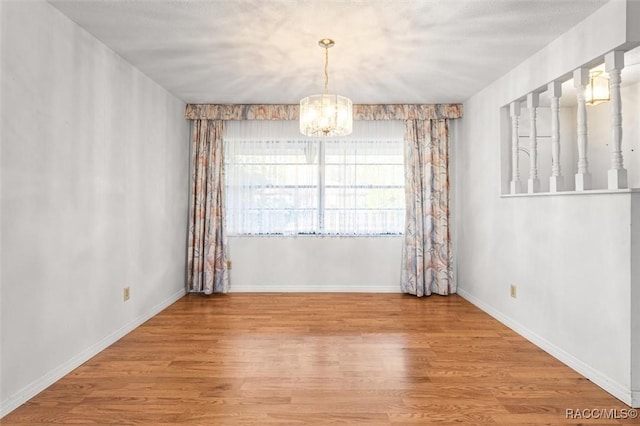 empty room featuring light hardwood / wood-style floors and an inviting chandelier