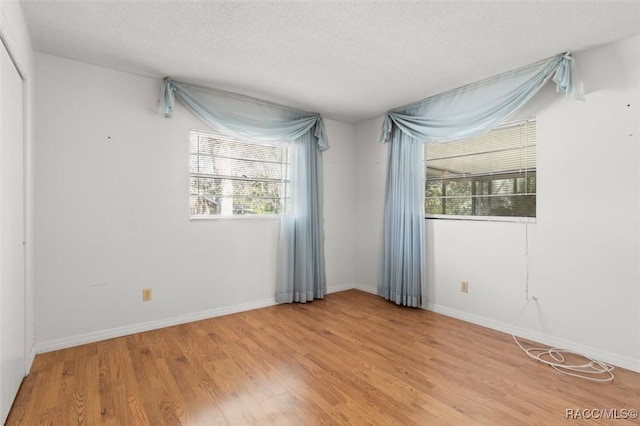 spare room featuring a textured ceiling and light hardwood / wood-style flooring