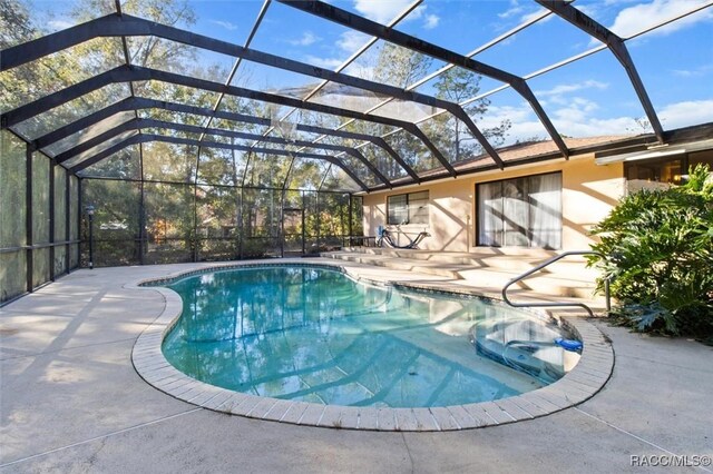 view of pool featuring glass enclosure and a patio