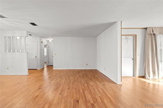 unfurnished living room with light hardwood / wood-style flooring and a textured ceiling