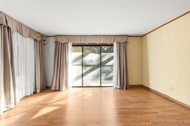 unfurnished room featuring a textured ceiling, light hardwood / wood-style floors, and crown molding