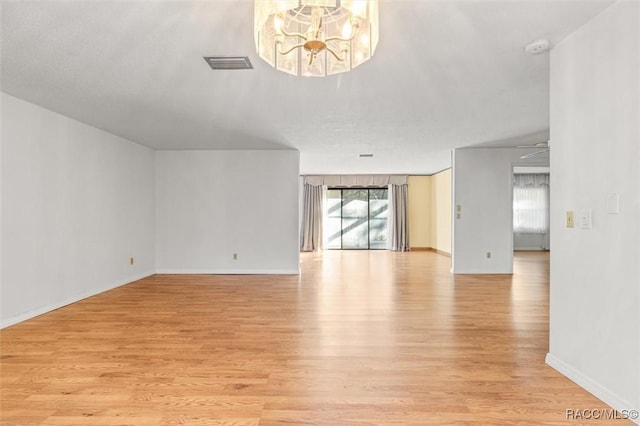 unfurnished living room featuring light wood-type flooring and an inviting chandelier