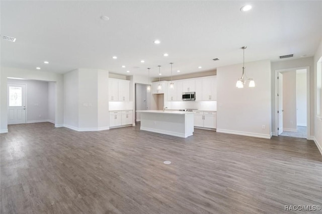 unfurnished living room featuring hardwood / wood-style flooring, sink, and an inviting chandelier