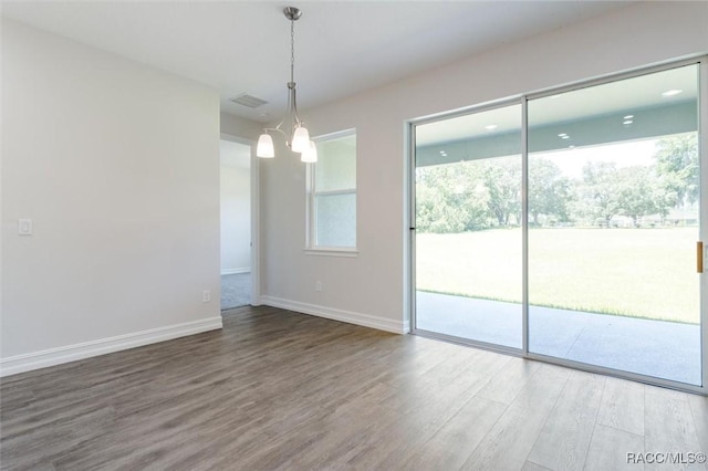 unfurnished room featuring hardwood / wood-style floors and an inviting chandelier