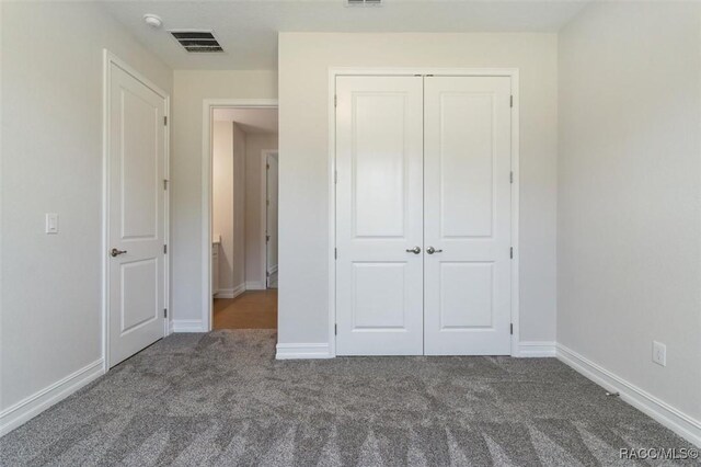 unfurnished bedroom with ensuite bathroom and dark colored carpet