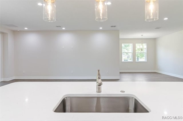 kitchen featuring wood-type flooring, hanging light fixtures, and sink