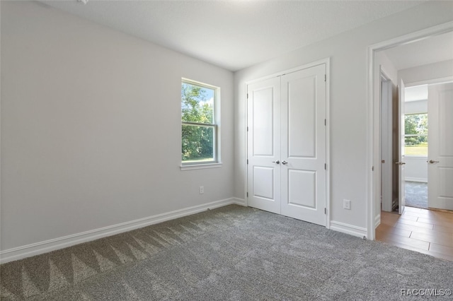 unfurnished bedroom with carpet flooring, a closet, and multiple windows