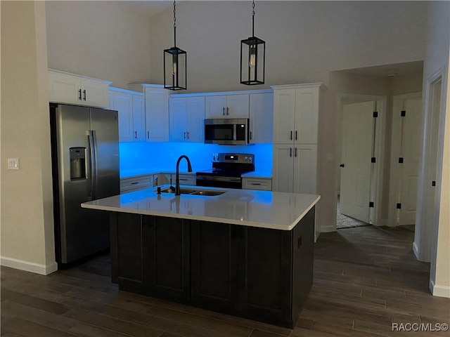 kitchen with white cabinetry, hanging light fixtures, stainless steel appliances, dark hardwood / wood-style flooring, and an island with sink