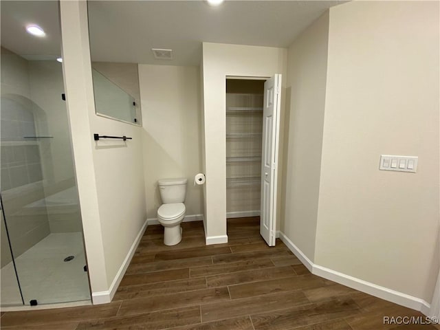 bathroom with a tile shower, wood-type flooring, and toilet