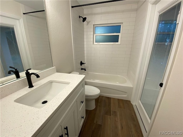 full bathroom featuring vanity, tiled shower / bath, wood-type flooring, and toilet