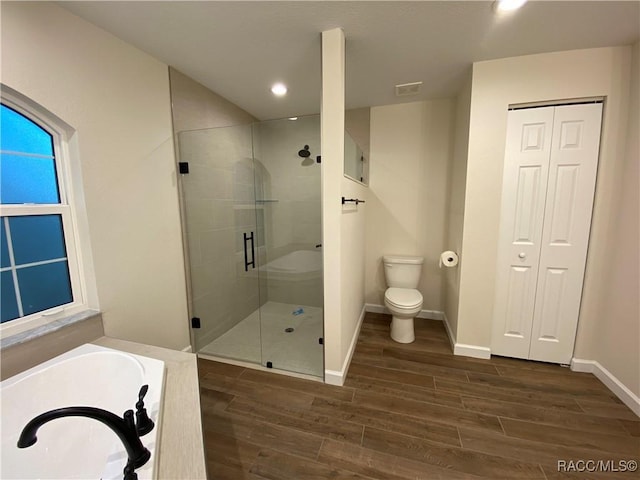 bathroom featuring hardwood / wood-style floors, plus walk in shower, and toilet