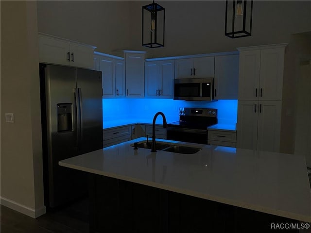 kitchen featuring pendant lighting, a center island with sink, sink, appliances with stainless steel finishes, and white cabinetry