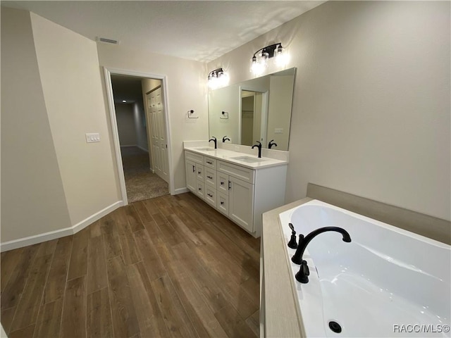 bathroom with a bathing tub, hardwood / wood-style floors, and vanity