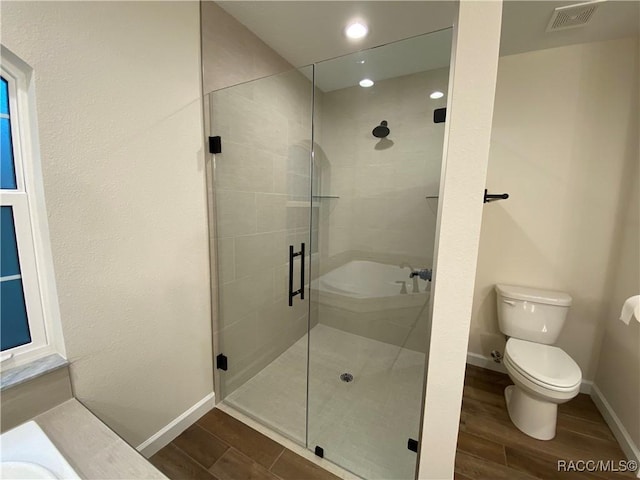 bathroom with toilet, a shower with door, and hardwood / wood-style flooring