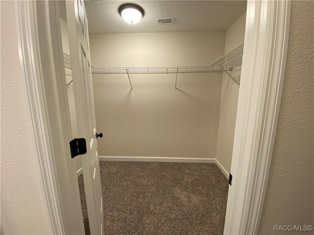 walk in closet with dark carpet