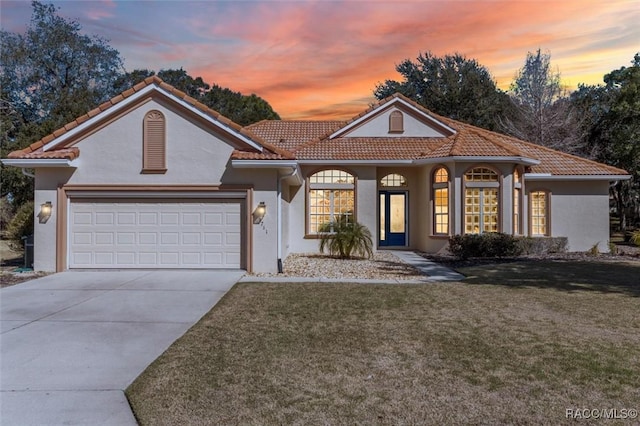 mediterranean / spanish-style house featuring a garage and a lawn