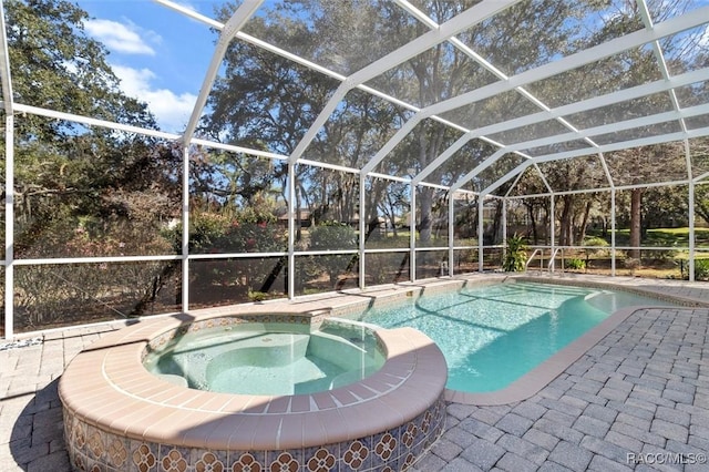 view of pool with a patio area, glass enclosure, and an in ground hot tub