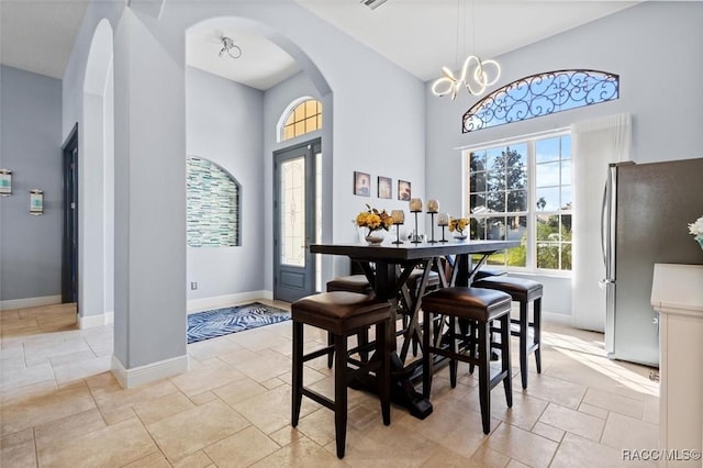 dining space with an inviting chandelier and a towering ceiling