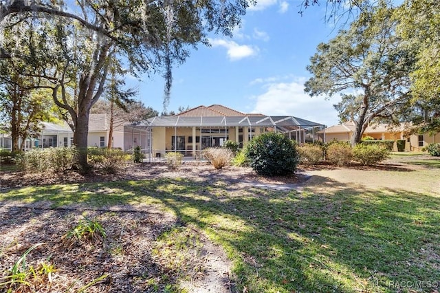 rear view of house with a lanai and a lawn