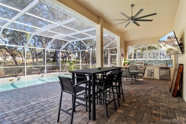 view of patio / terrace with area for grilling, ceiling fan, and glass enclosure