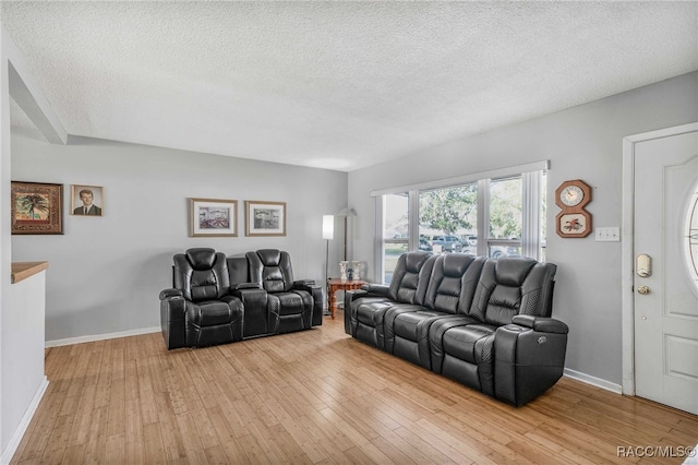 living area featuring baseboards, a textured ceiling, and light wood finished floors