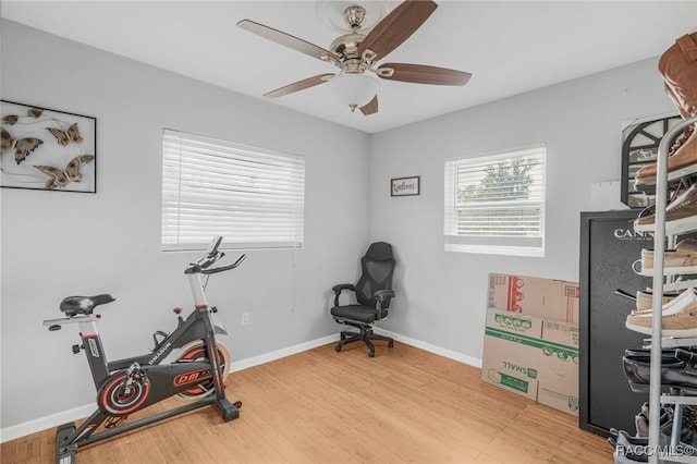 exercise room with a ceiling fan, light wood-style flooring, and baseboards