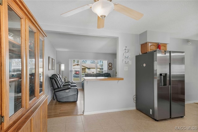 kitchen with light tile patterned floors, stainless steel fridge, baseboards, a ceiling fan, and a textured ceiling