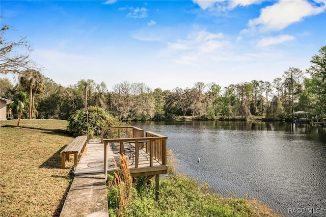 view of dock with a water view and a lawn