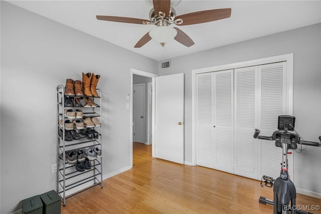 workout area featuring baseboards, visible vents, ceiling fan, and wood finished floors