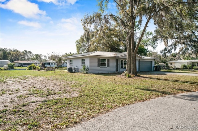 ranch-style home with an attached garage, central air condition unit, driveway, and a front lawn