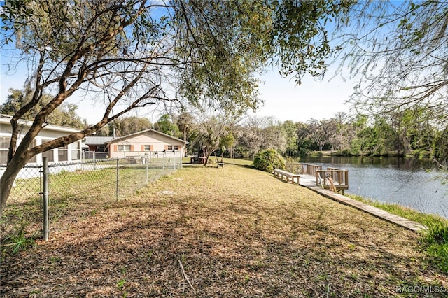 view of yard featuring a dock, a water view, and fence