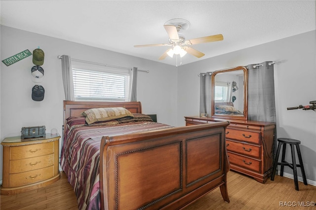 bedroom with a ceiling fan, baseboards, and light wood finished floors