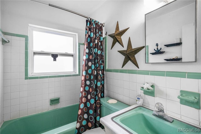 bathroom with toilet, shower / tub combo, a sink, tile walls, and wainscoting