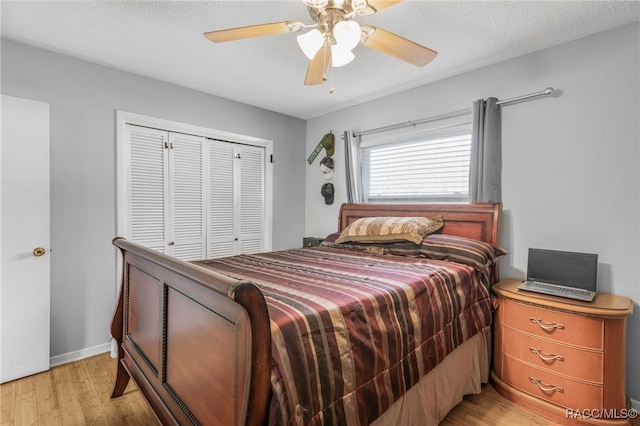 bedroom featuring a closet, light wood-style flooring, a ceiling fan, a textured ceiling, and baseboards