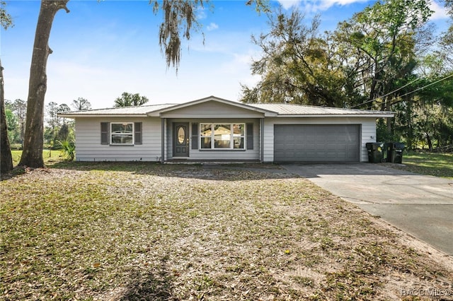 ranch-style home featuring a garage, metal roof, and concrete driveway